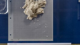 Eine Handvoll Sand liegt auf einem Millimeterpapier 